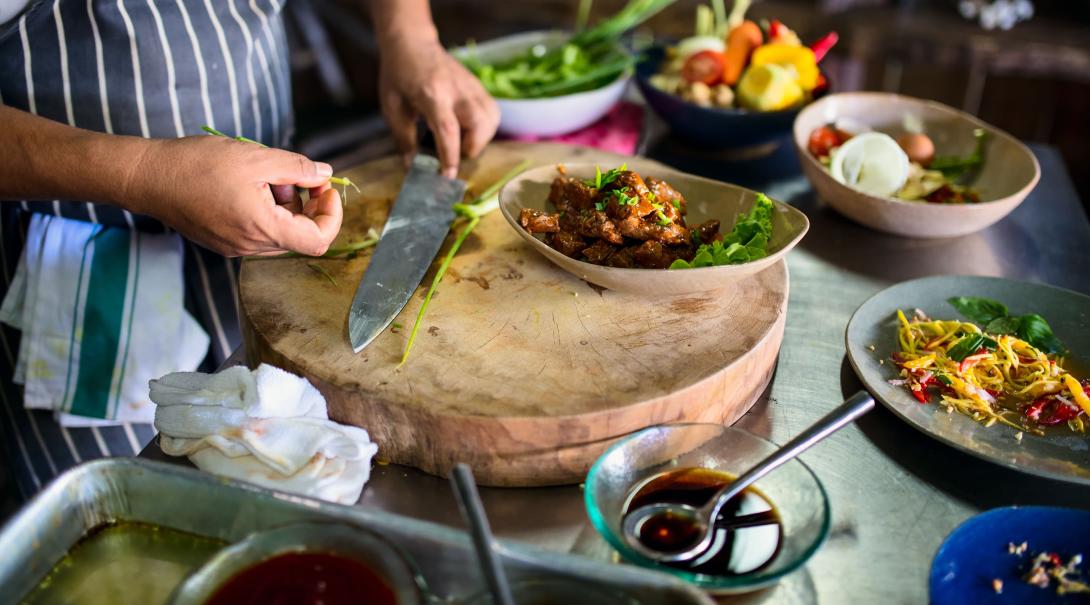 A chef teaches travellers how to cook a traditional Cambodia meal during a cooking lesson. A chef prepares a traditional Cambodian meal using organic ingredients.